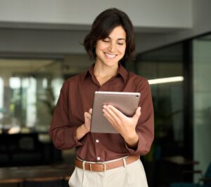 Happy busy female professional manager using tab standing in office.