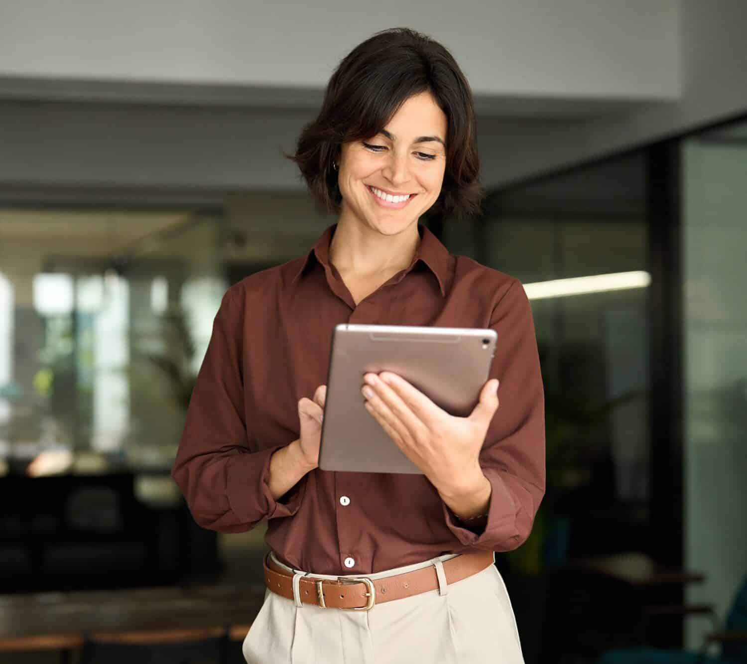 Happy busy female professional manager using tab standing in office.