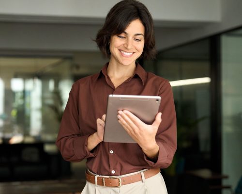 Happy busy female professional manager using tab standing in office.
