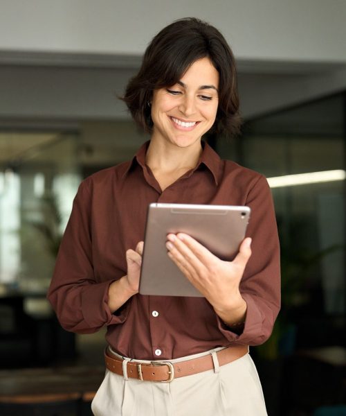 Happy busy female professional manager using tab standing in office.